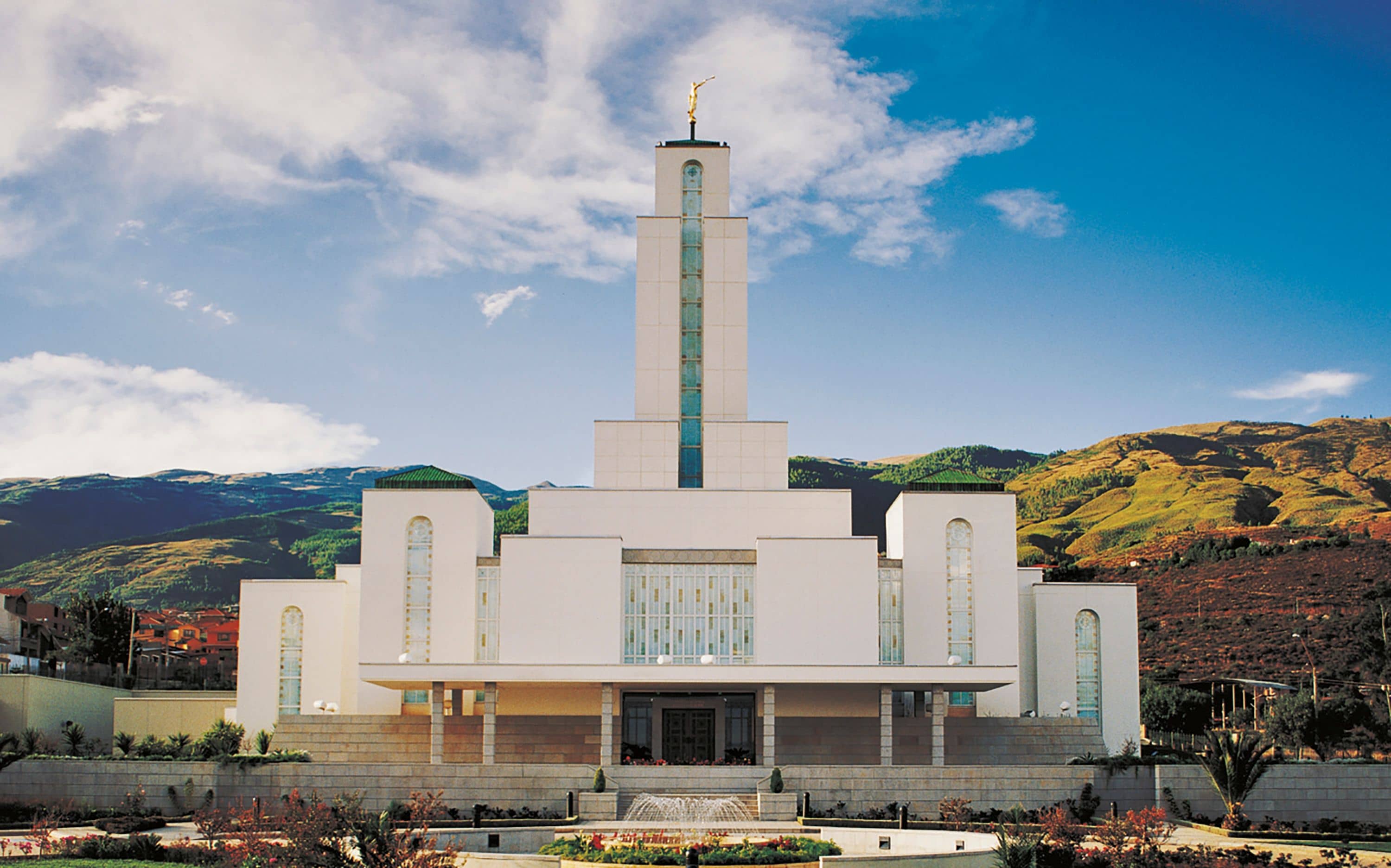 The Cochabamba Bolivia Temple, a white building with a central tower topped by a golden statue of an angel blowing a trumpet.