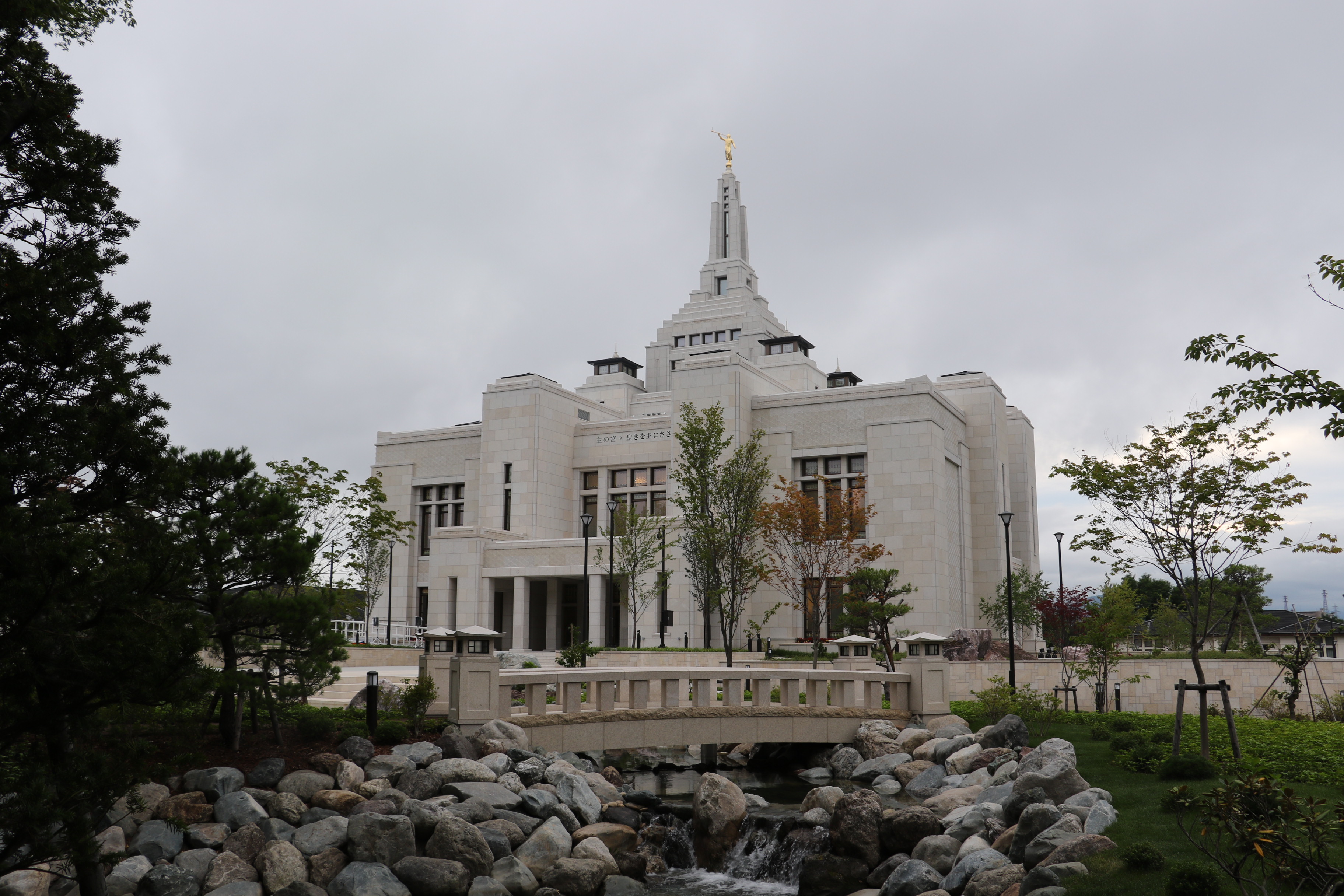 The Sapporo Japan Temple, a white building with a spire topped by a golden statue of an angel blowing a trumpet.