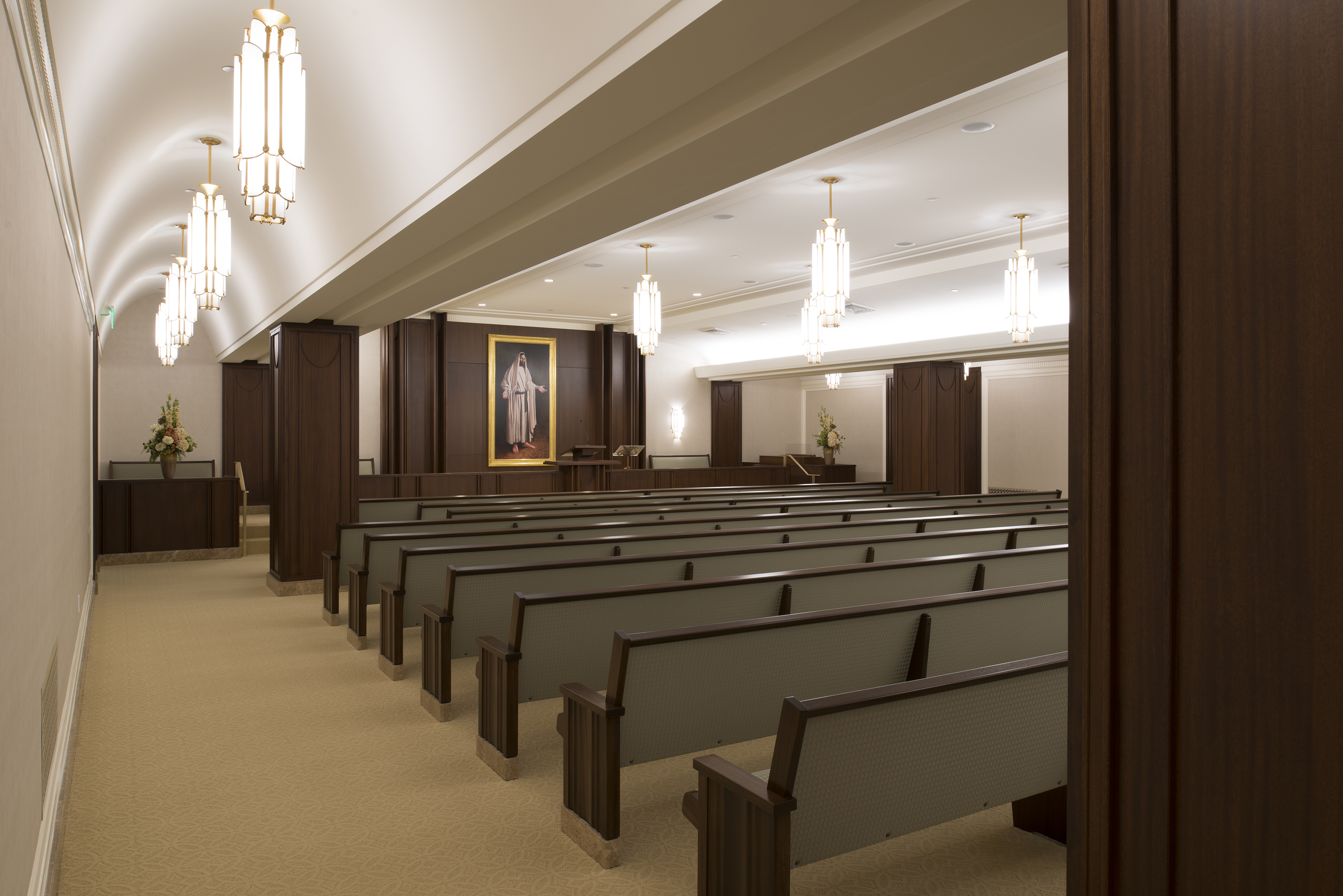 A chapel with many pews to sit, with a pulpit and painting of Christ at the front of the room.