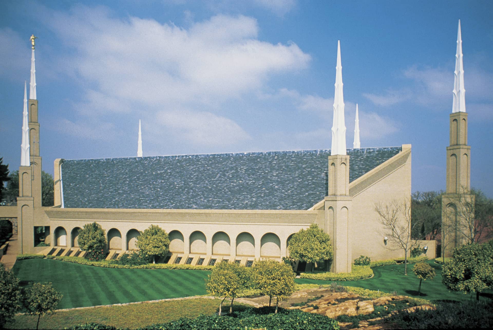The Johannesburg South Africa Temple, a white building with a peaked blue roof and six tall, detached spires around the exterior.