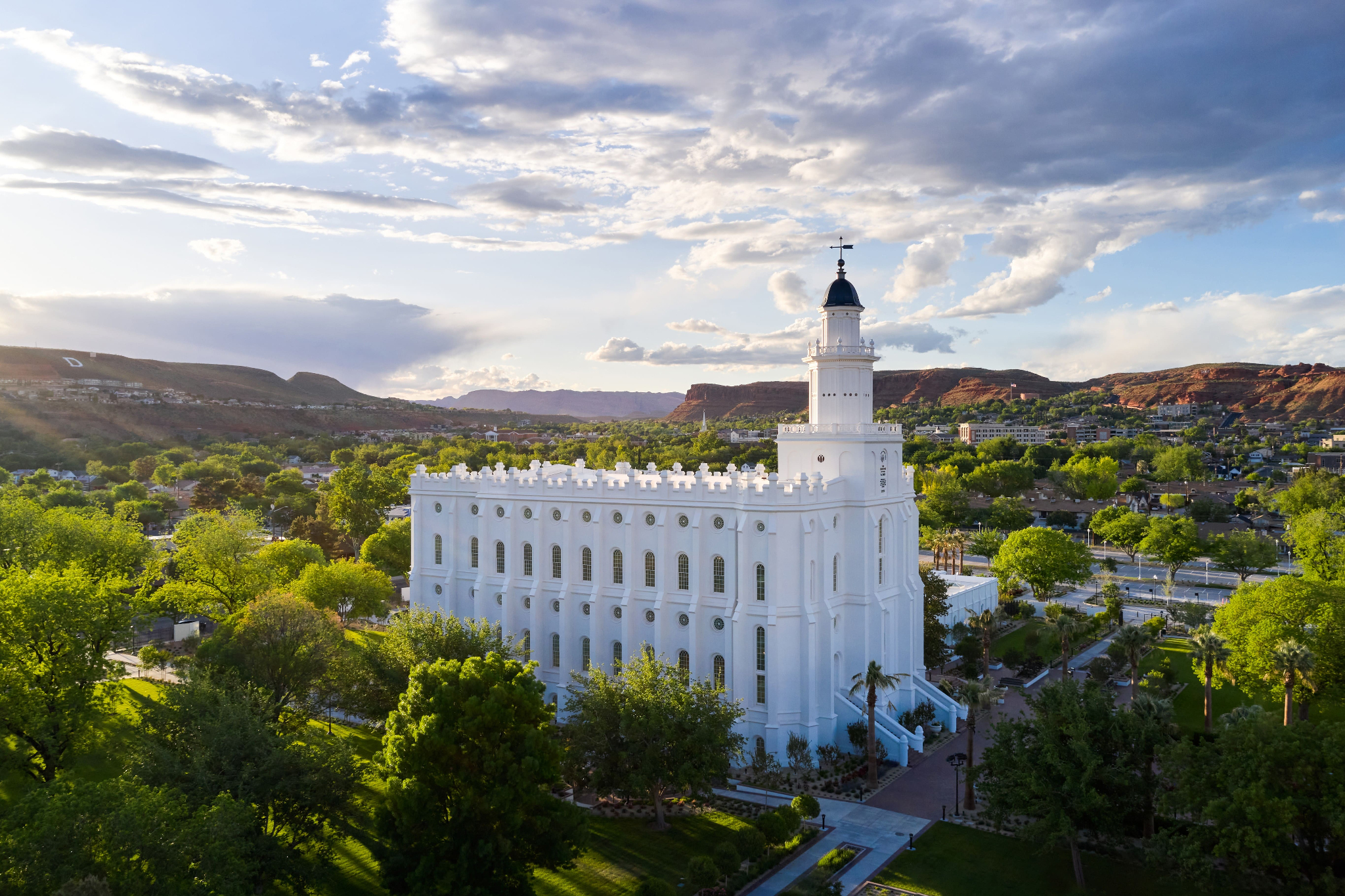 The exterior of the St. George Utah Temple, a white rectangular building with a domed spire and blue cap on one side.