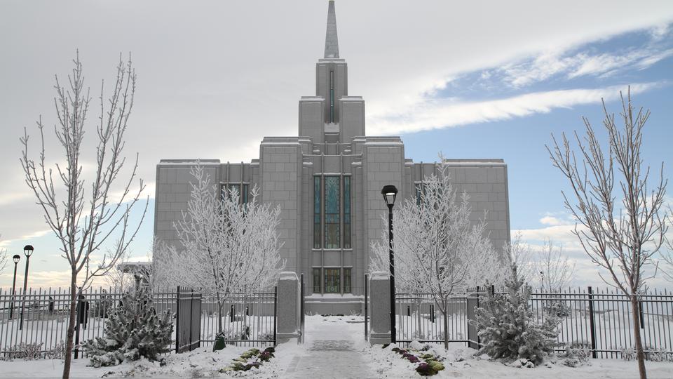 The Calgary Alberta Temple, a white building with a spire topped by a statue of a golden angel blowing a trumpet.