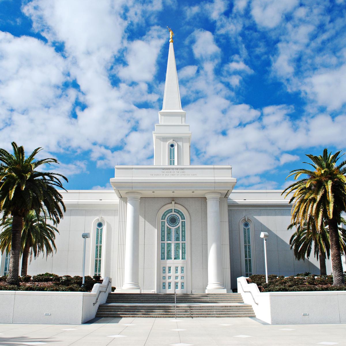 The exterior of the Orlando Florida Temple, a white building with arched windows around it and a tower with a square base on top. 