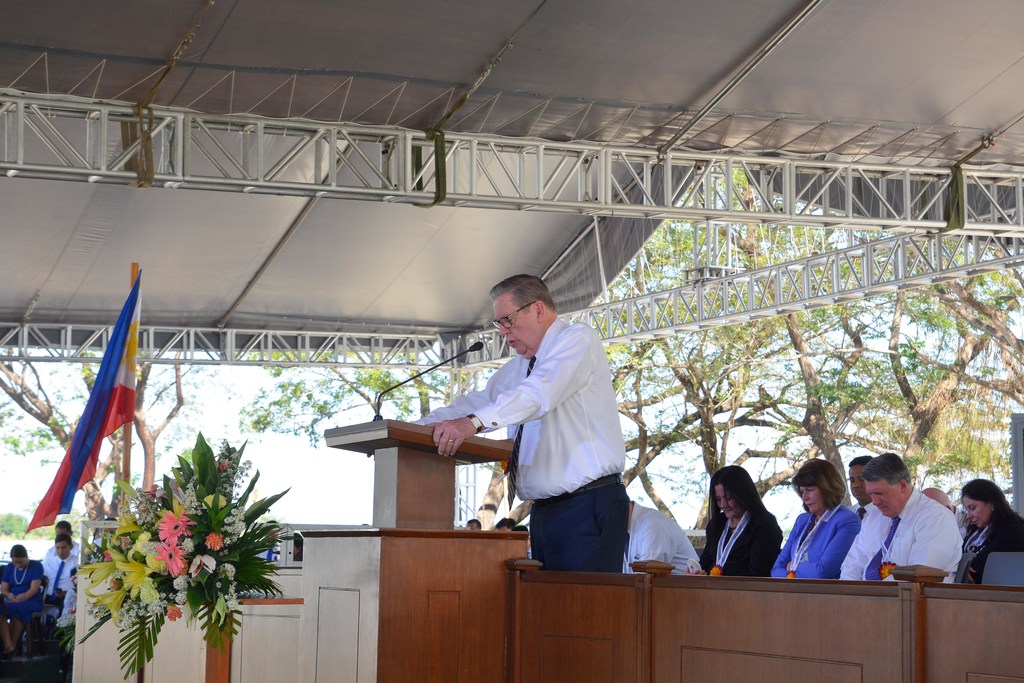Elder Jeffrey R. Holland at a pulpit praying and dedicating the Urdaneta temple's site for ground to be broken.