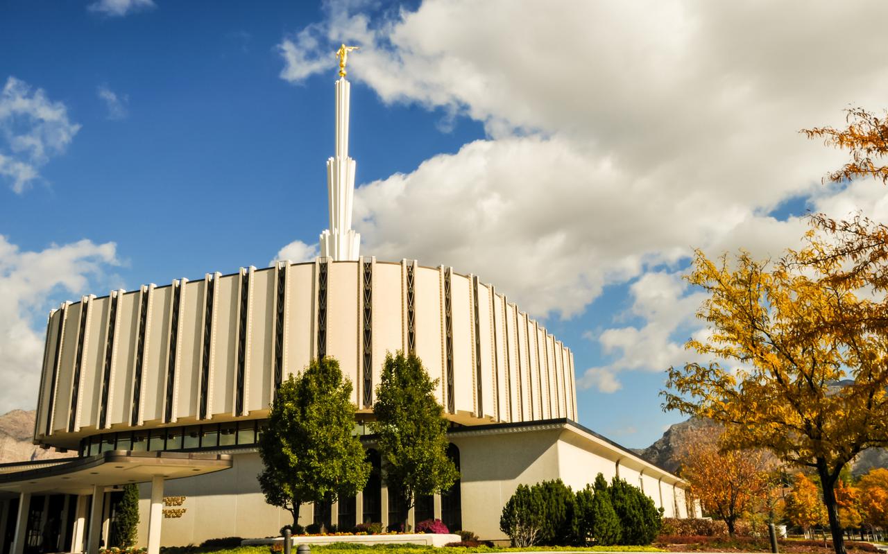 The exterior of the original Ogden Utah Temple, dedicated in 1972, that had a flat, round base with a spire in the center, during autumn.