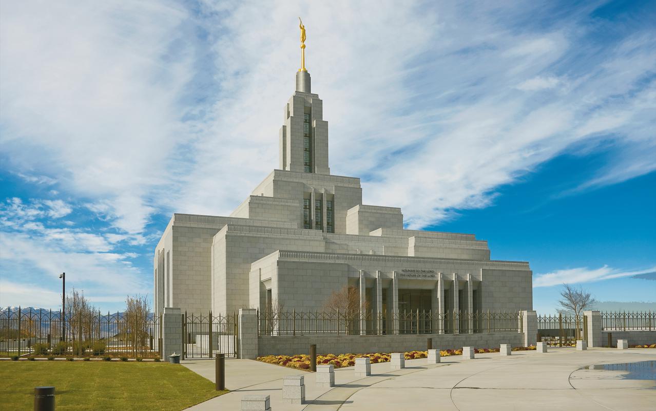 The exterior of the Draper Utah Temple, a multilevel building with long, rectangular windows and a rectangular tower above the center.