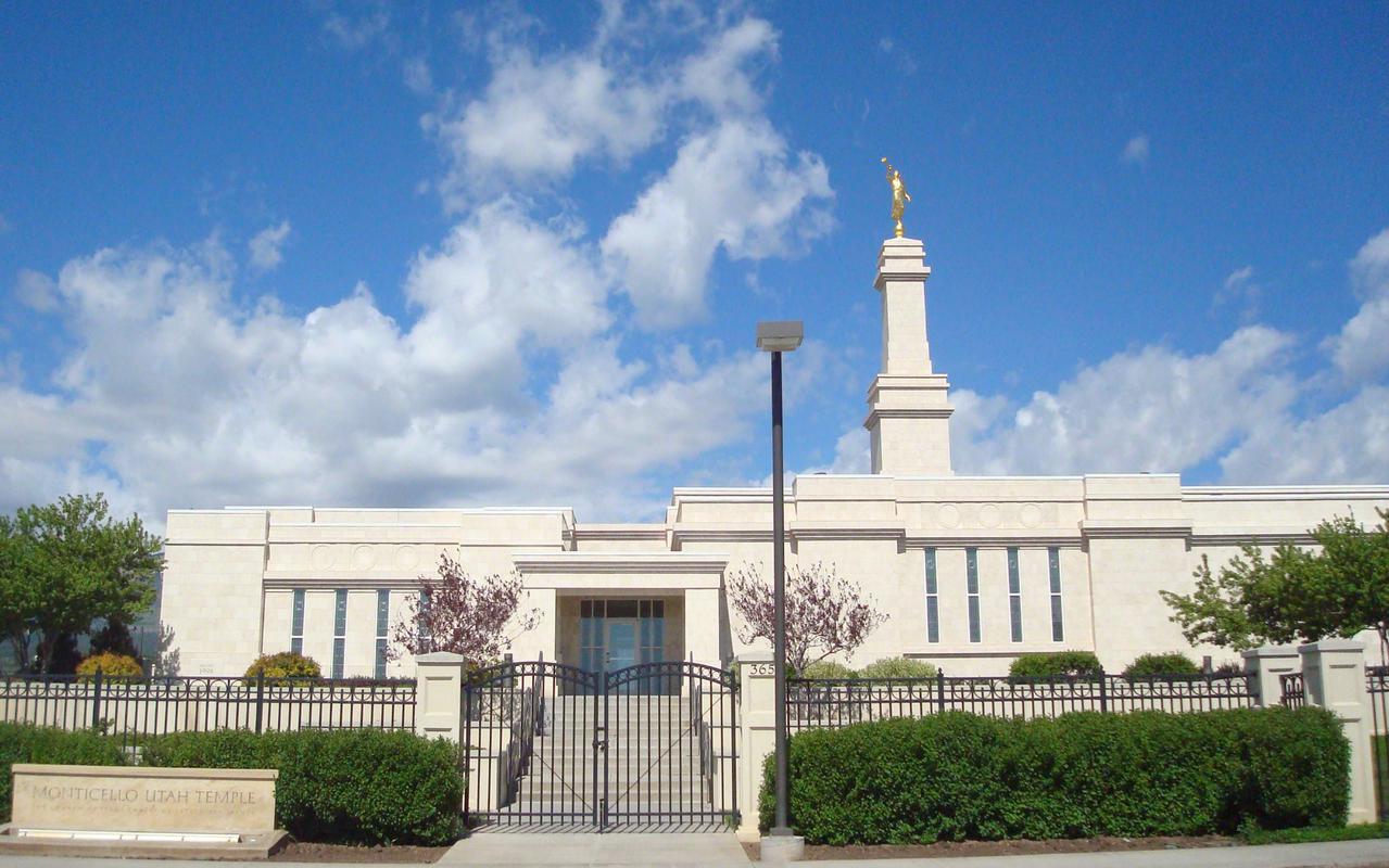 The exterior of the Monticello Utah Temple, an off-white marble building of one story, with a center spire on a square base.