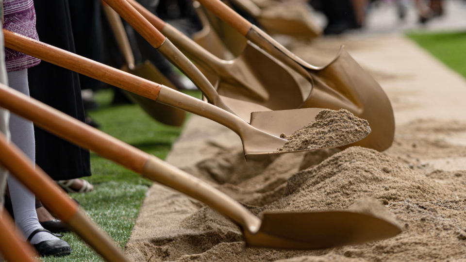A close-up of the ceremonial golden shovels digging into piles of dirt at the Miraflores temple groundbreaking.