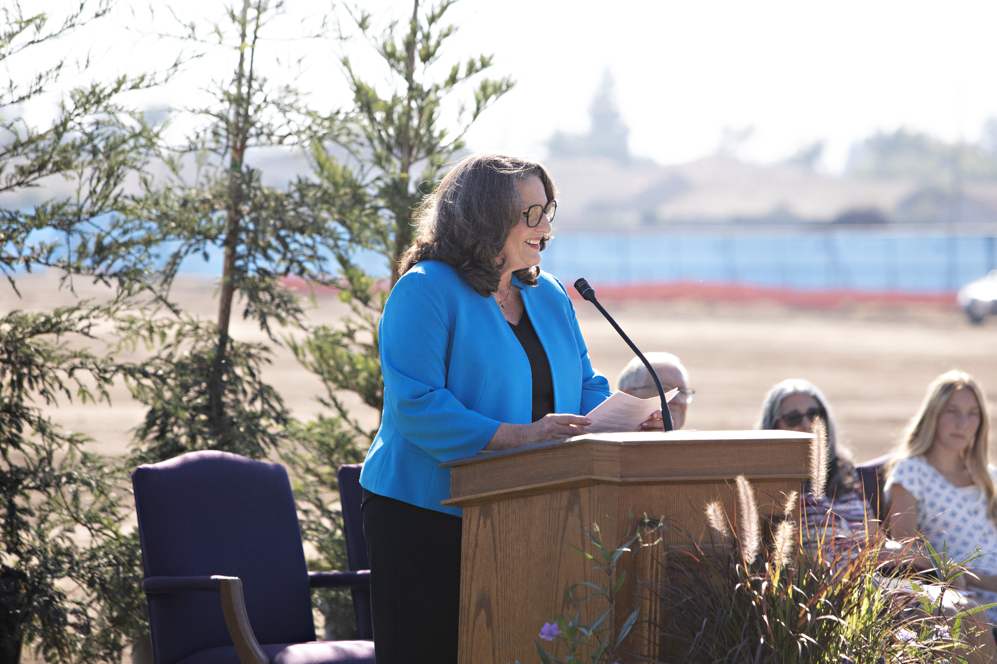 Modesto city Mayor Sue Zwahlen wearing a blue blazer and speaking at a pulpit outside.