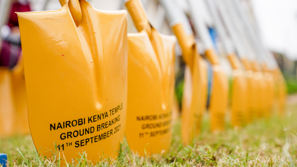A close-up of the head of ceremonial golden shovels with the text "Nairobi Kenya Temple Groundbreaking, 11th September, 2021" printed on them.