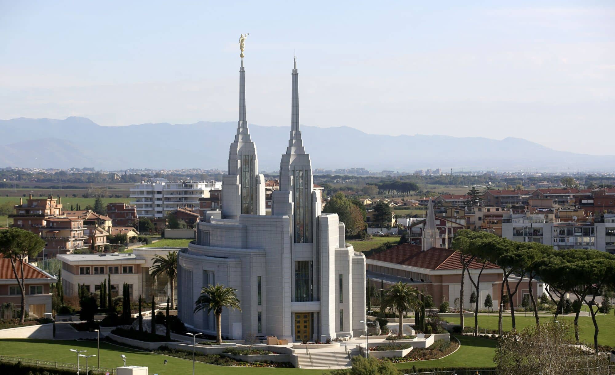 The exterior of the Rome Italy Temple, an oval building with a spire on each of the two ends.