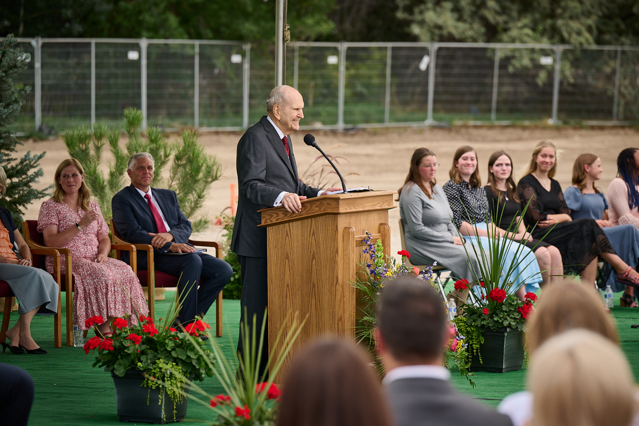 President Nelson wearing a suit and tie and speaking from a pulpit outside.