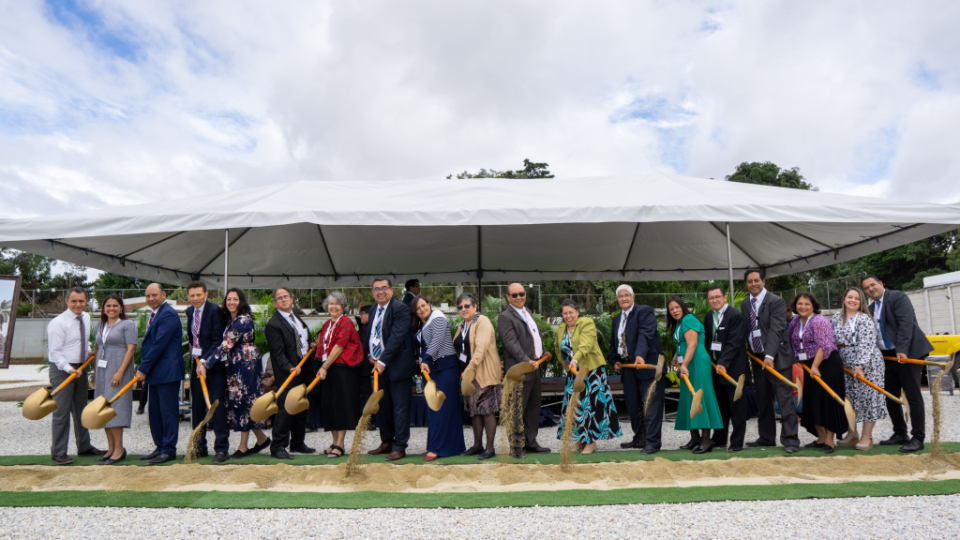A line of invited guests holding ceremonial golden shovels and digging in the ground to break ground on the Miraflores temple.