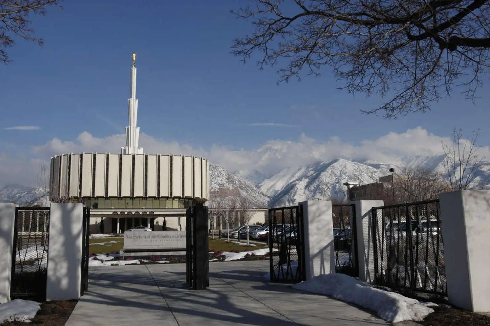 An open gate with the original Ogden Utah Temple, dedicated in 1972 — that had a flat, round base with a spire in the center — in the background.