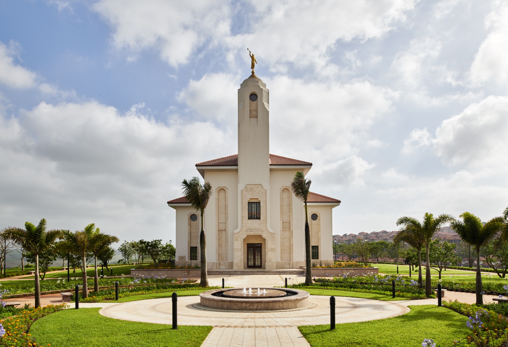 The Durban South Africa Temple, a white building with a central tower topped by a golden statue of an angel blowing a horn.