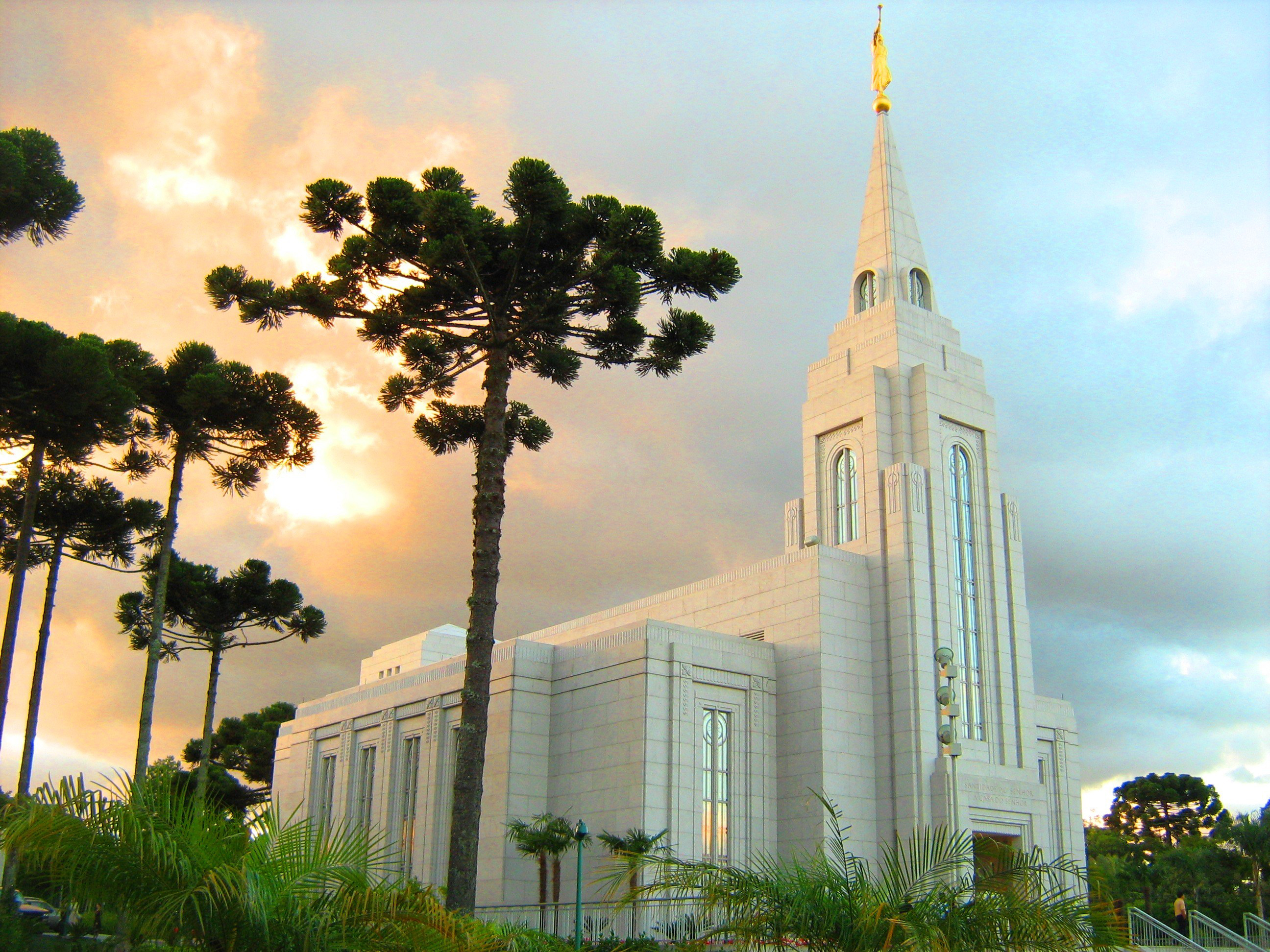 The Curitiba Brazil Temple, a white building topped by a golden statue of an angel blowing a horn.