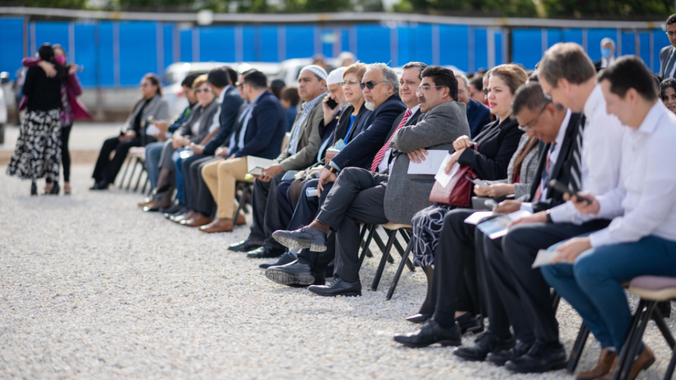 A congregation sitting on chairs outside on the Miraflores temple site before the groundbreaking.