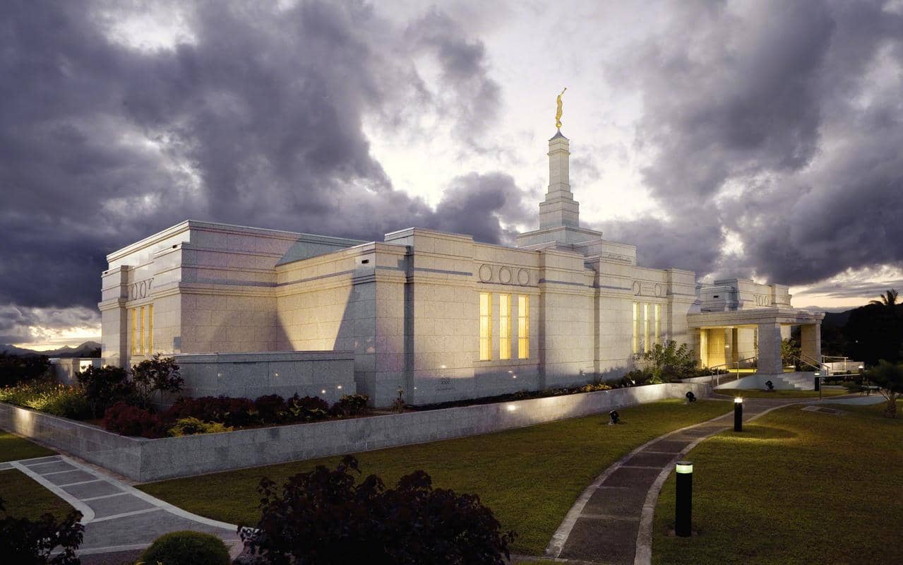 The Suva Fiji Temple, a white building with a spire topped by a golden statue of an angel blowing a trumpet.