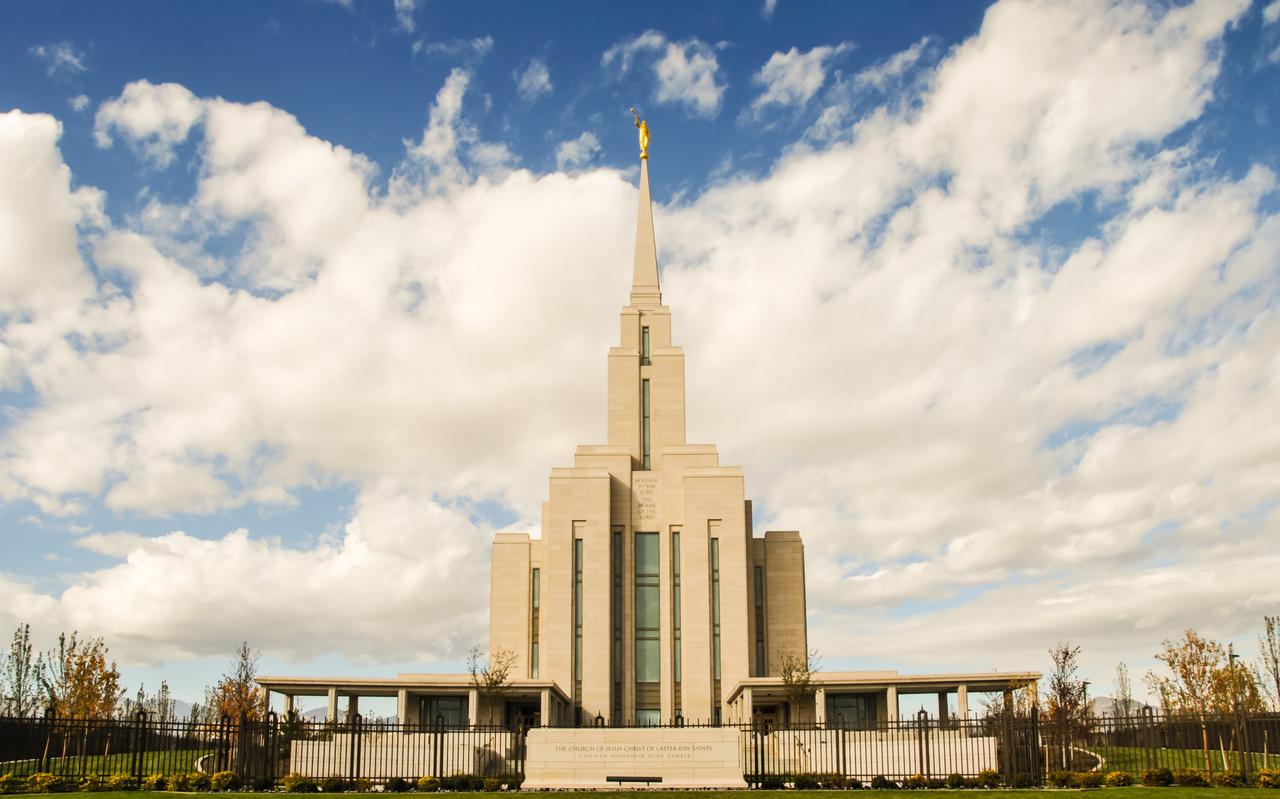 The Oquirrh Mountain Utah Temple, a white building with a steeple topped by a statue of a golden angel blowing a trumpet.