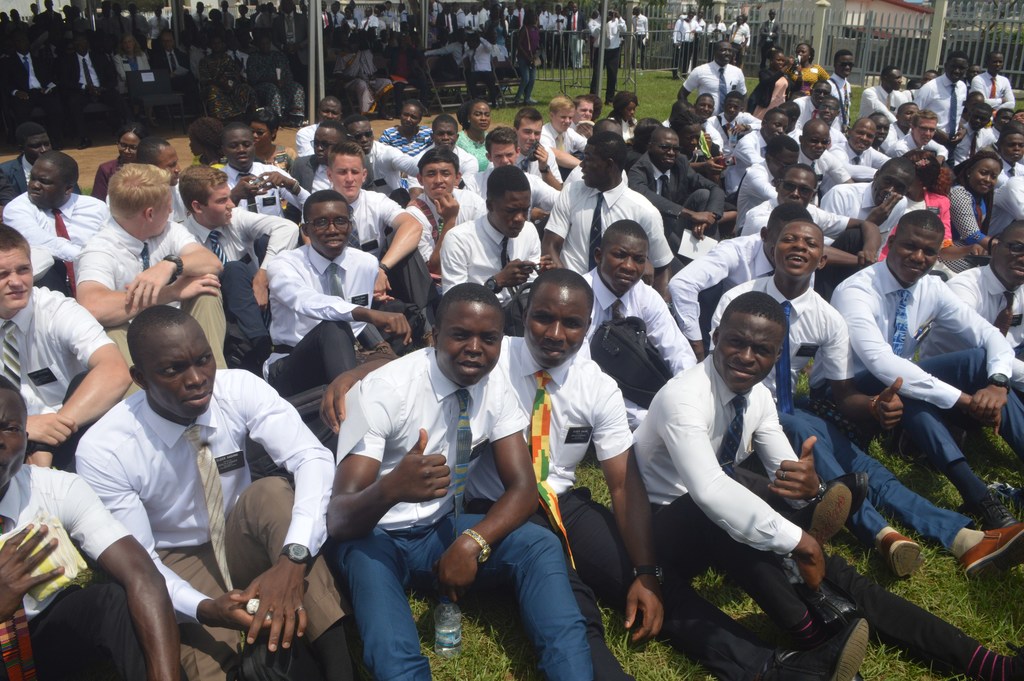 Missionaries sitting on the grass next to the groundbreaking site of the Abidjan Ivory Coast Temple.