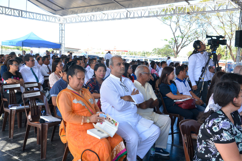 Church members sitting in chairs outside in a congregation as they listen to the Urdaneta Philippines Temple groundbreaking ceremony.