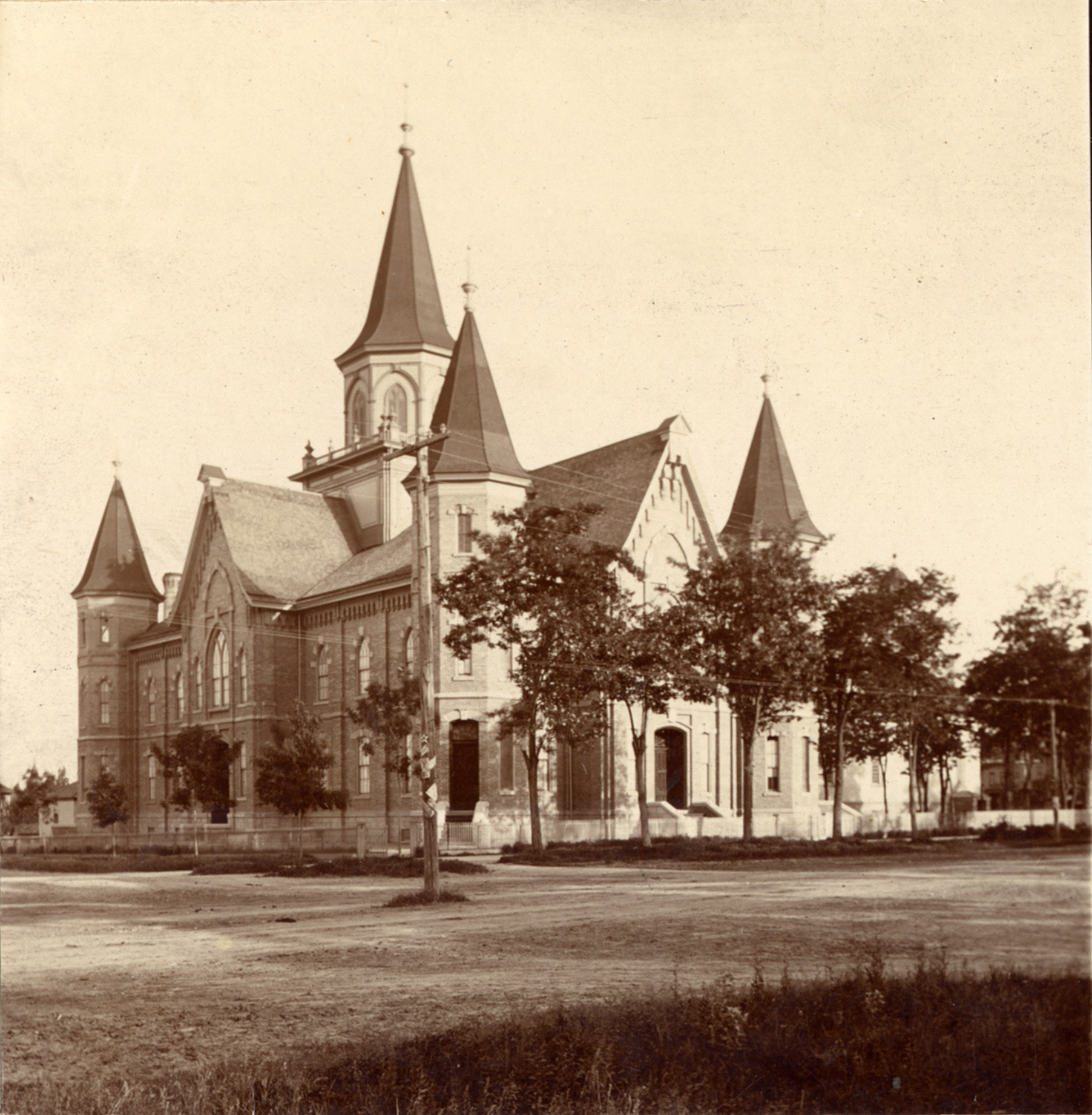 An old, black-and-white photograph of the Provo Tabernacle, a brick building with slanted roofs and five towers.