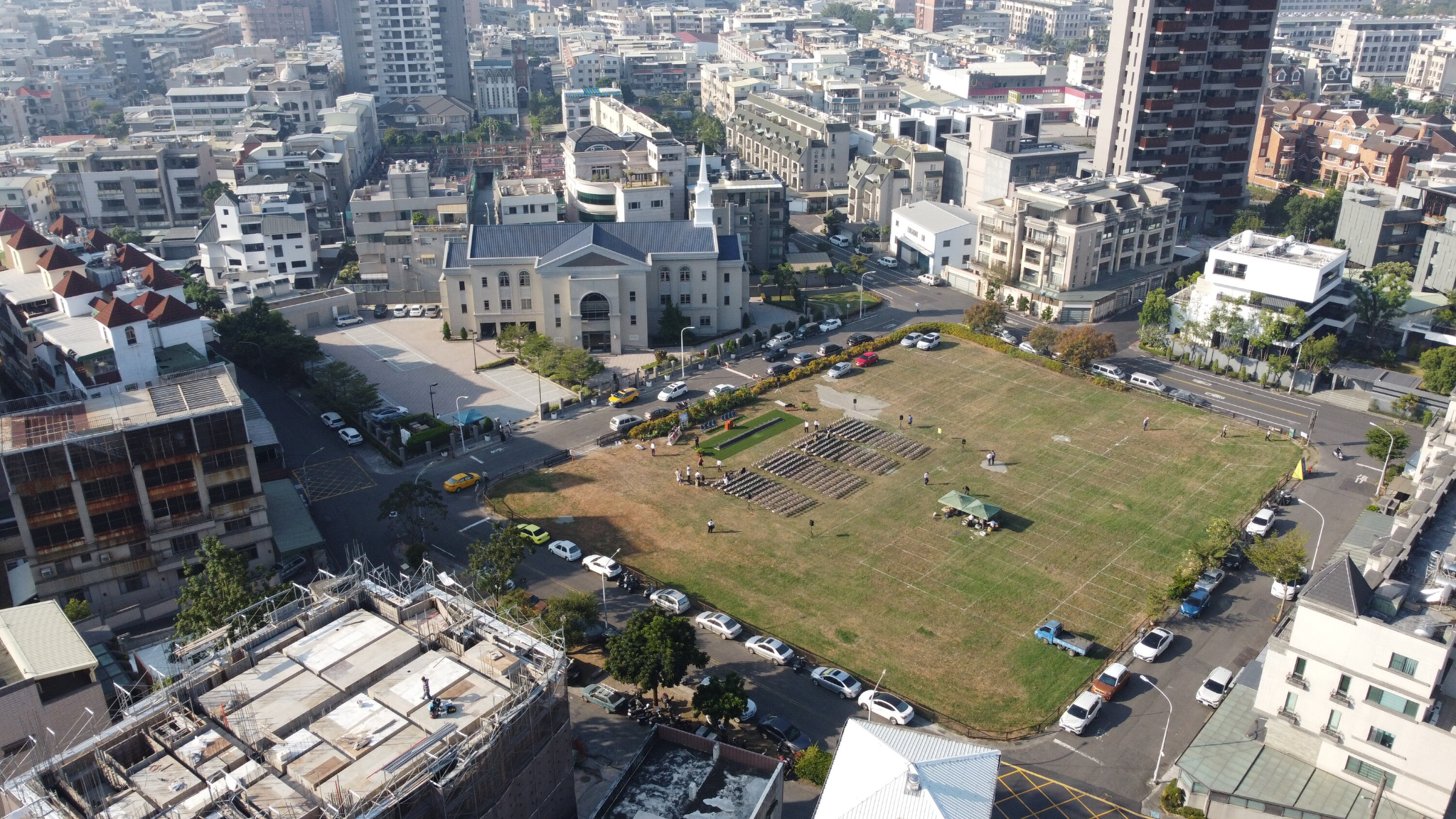 An aerial view of a grass field with buildings around it.