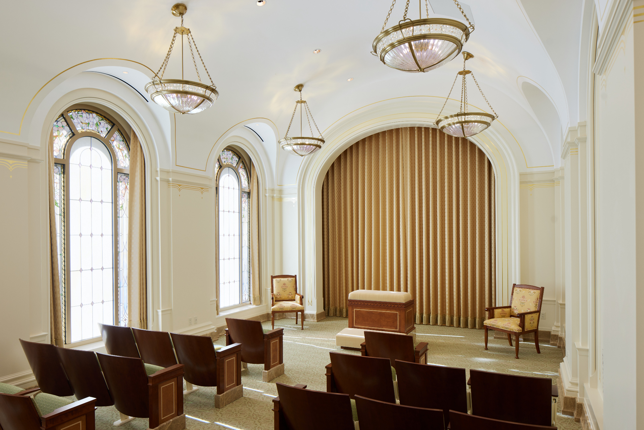 A white room with dark-wood seats and a wood altar in the Feather River California Temple.