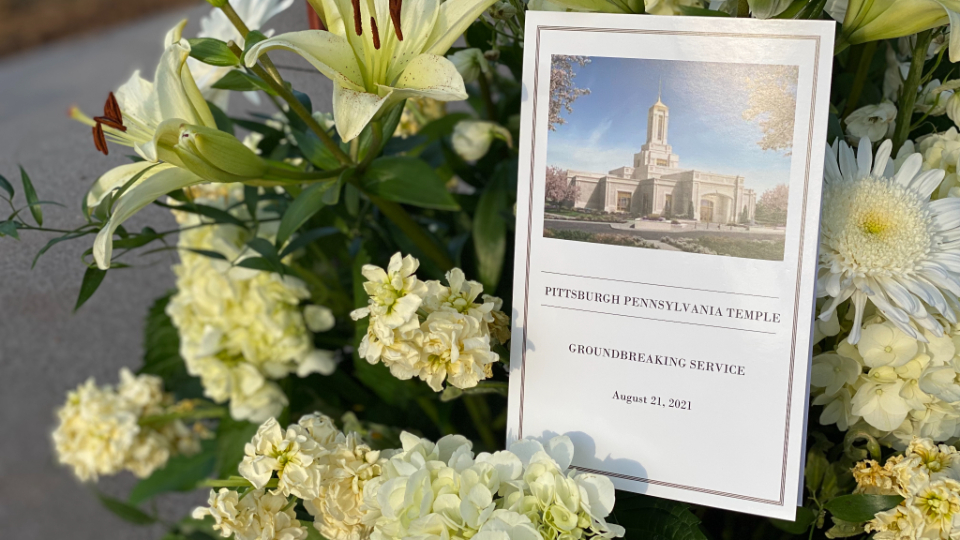 A close-up of a bouquet of flowers next to a paper program that says "Pittsburgh Pennsylvania Temple Groundbreaking Service."