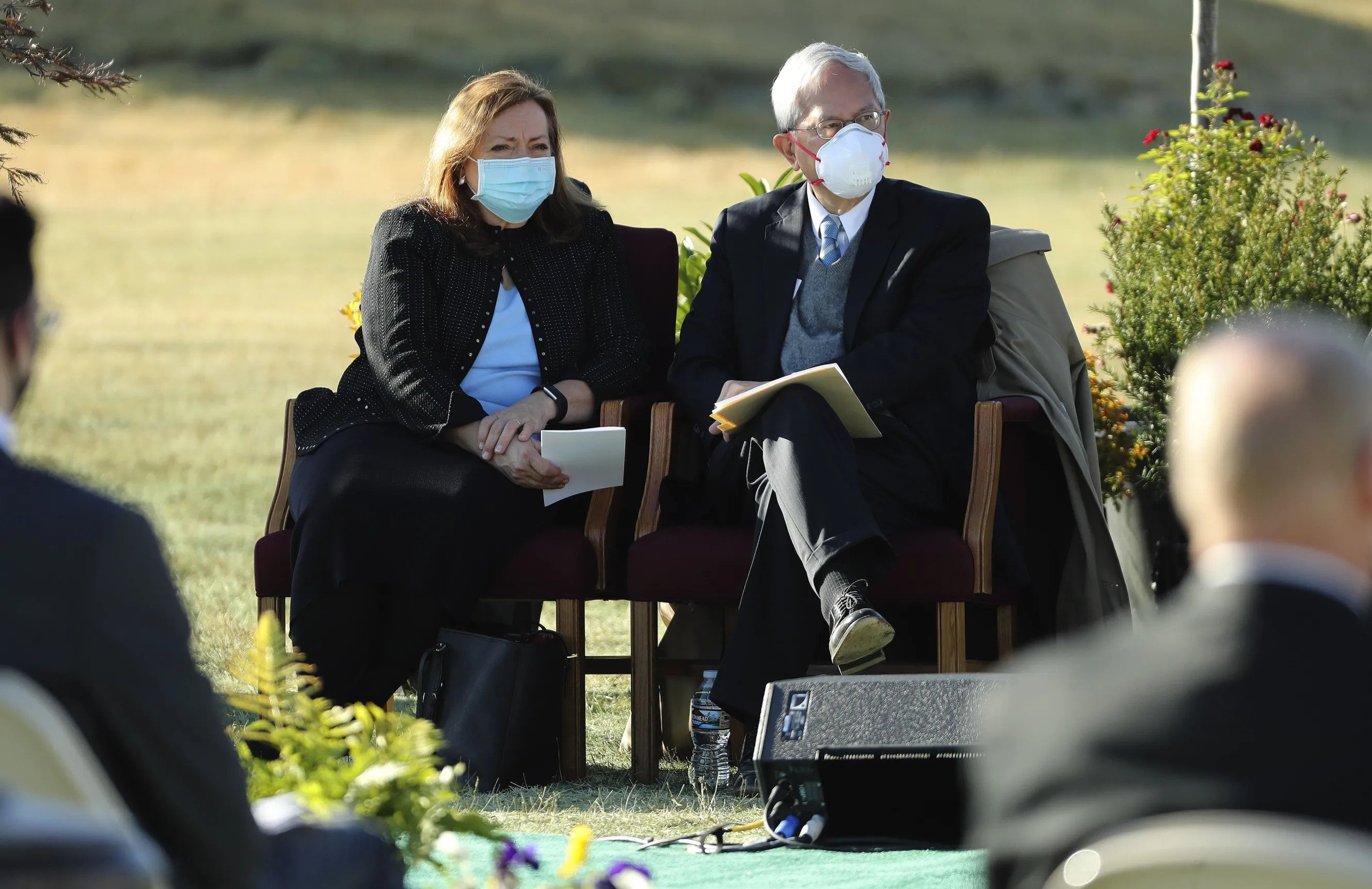 Elder and Sister Gong wearing face masks and sitting next to each other on chairs outside.