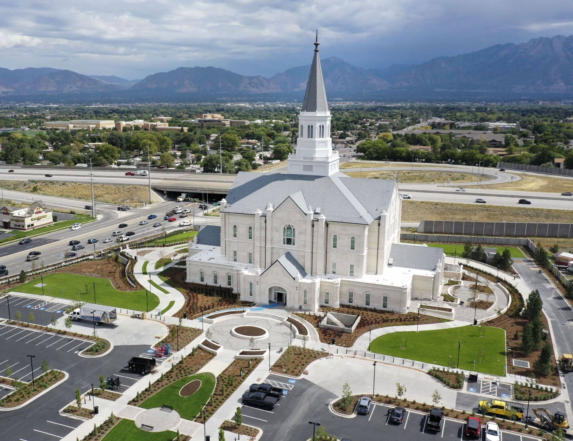 An aerial view of the Taylorsville Utah Temple, an off-white multistory building with a pointed tower above the center.