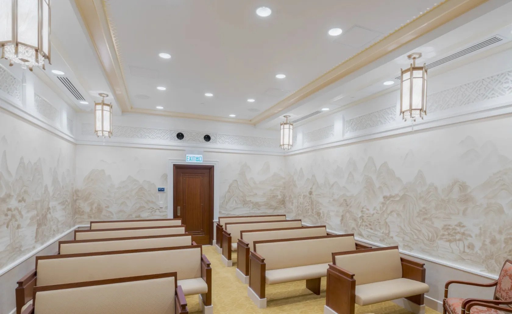 An instruction room inside the Hong Kong temple, with two rows of pews and a mural of mountains on the walls.