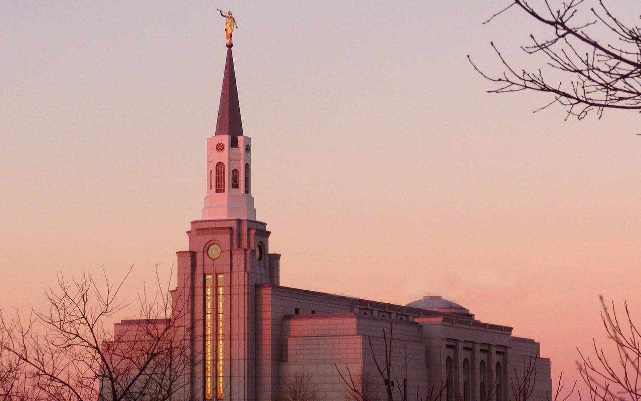 The Boston Massachusetts Temple, a white building with a blue steeple topped by a golden statue of an angel blowing a trumpet.