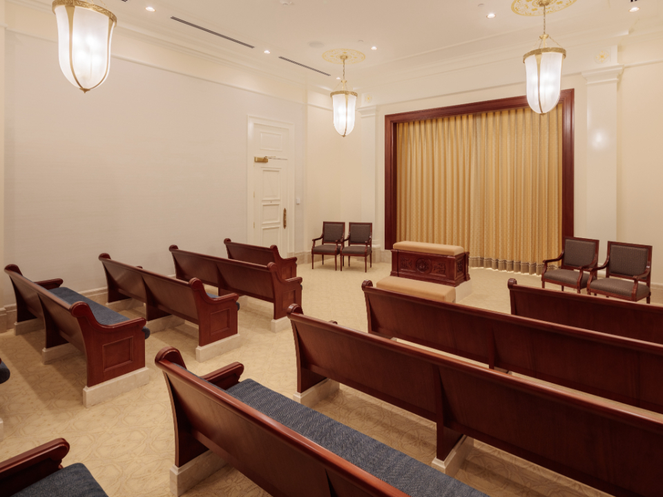 A room with two rows of pews, a temple altar and a curtain built into a wall.